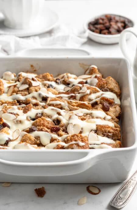 A white square baking dish of bread pudding with raisins.