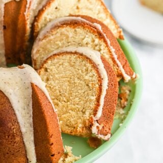 slices of brown sugar pound cake on a green cake stand on a white background