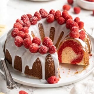 White chocolate raspberry bundt cake with slice missing on a white plate